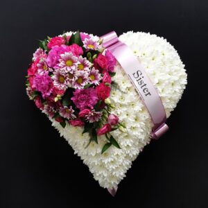 White chrysanthemum heart funeral tribute with pink flowers and Sister ribbon on a black background