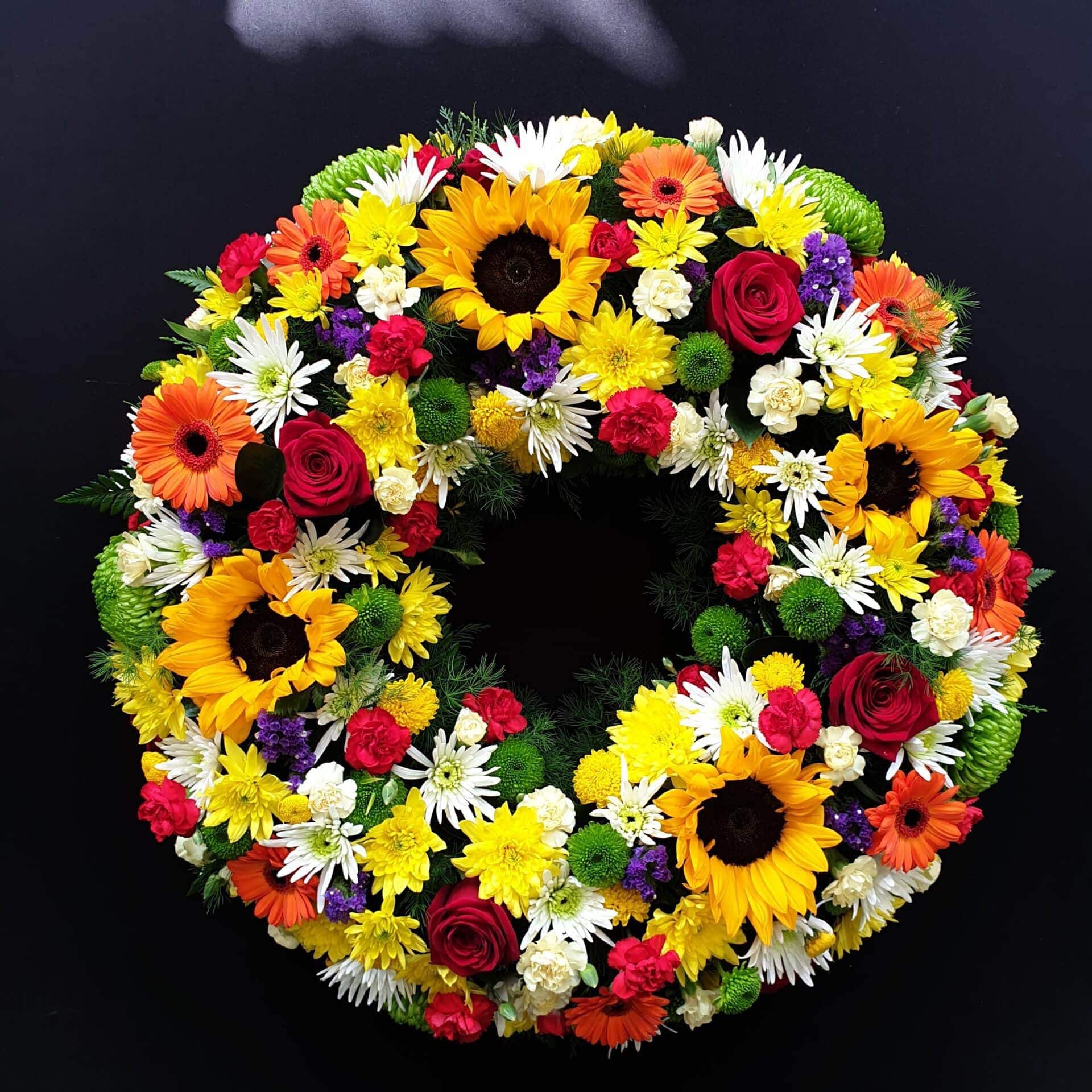 Bright multicoloured funeral wreath with sunflowers, gerberas, roses and chrysanthemums