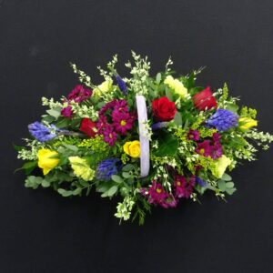 Vibrant mixed funeral flower basket with red, yellow and purple flowers in a handled basket from Anastasia Florists Aberdeen.