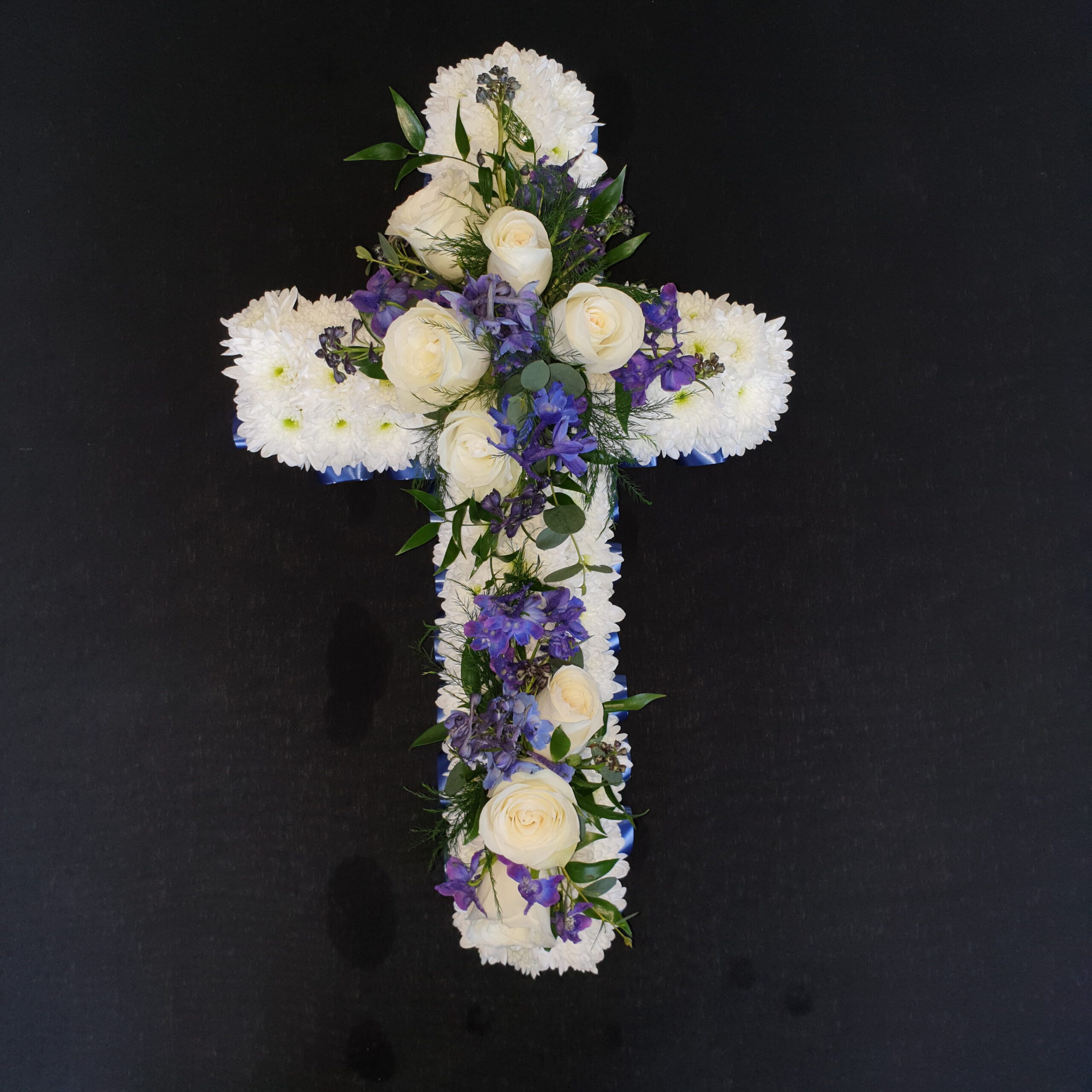 White and blue funeral cross with chrysanthemum base, white roses and purple-blue flowers