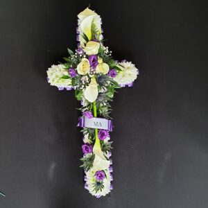 White and purple funeral cross with chrysanthemum base, roses, calla lilies and name ribbon