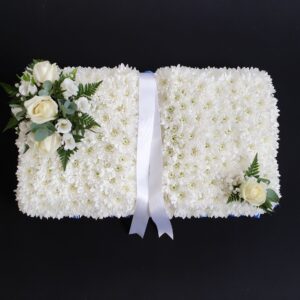White rose funeral book tribute with massed chrysanthemum base and central white ribbon