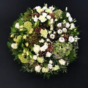Woodland-style white and green funeral posy with roses, hydrangea and pine cones
