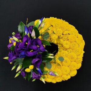 Yellow chrysanthemum based funeral wreath with purple flower spray